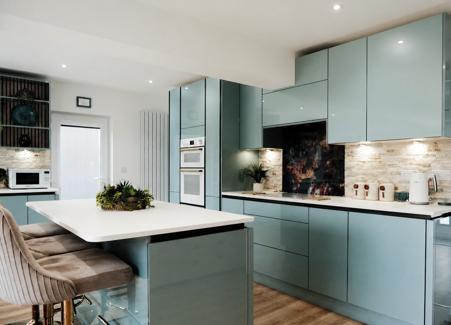 Duck-egg blue high-gloss handleless kitchen with an island breakfast bar, velvet stools and a brick-effect stone splashback with dark marble feature panel